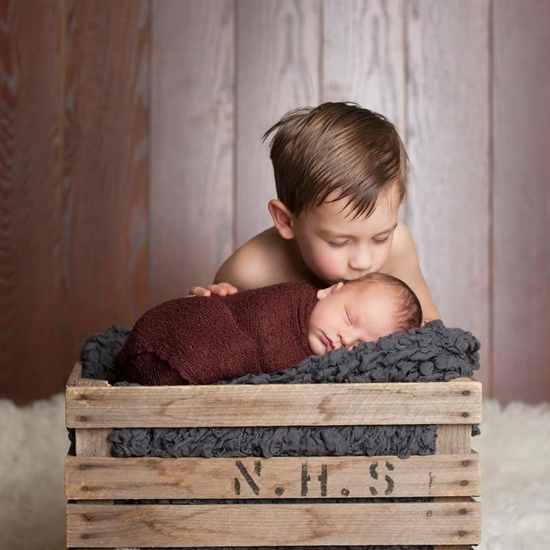 A big brother kissing his sleeping newborn sibling